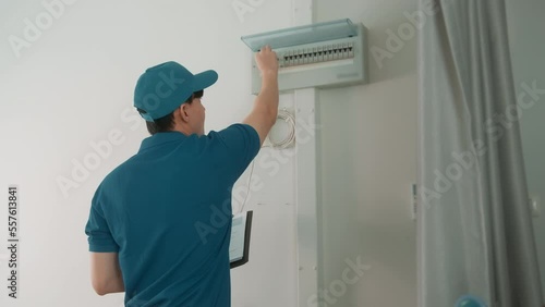 An Asian young Technician service man wearing blue uniform checking electrical appliances in home