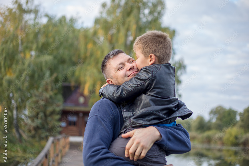 Happy father and son hugging and playing together in green nature. Fisherman's house with a wooden pedestrian bridge on a tiny island in the middle of the lake. Happy father and son hugging and playing together in green nature. Fisherman's house with a wooden pedestrian bridge on a tiny island in the middle of the lake.