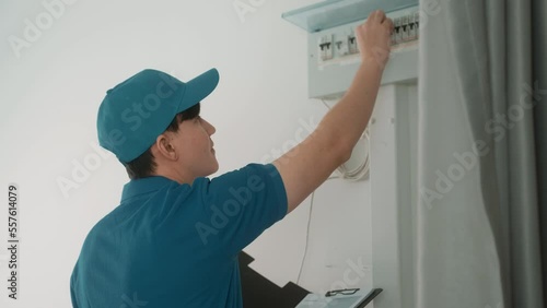 An Asian young Technician service man wearing blue uniform checking electrical appliances in home