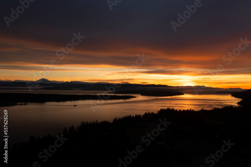 Sunrise Aerial View of Lummi Island and the Mainland With a Ferryboat Making a Morning Crossing. Just before the sun rises over the Cascade Mountains dramatic clouds form in the east and south. 