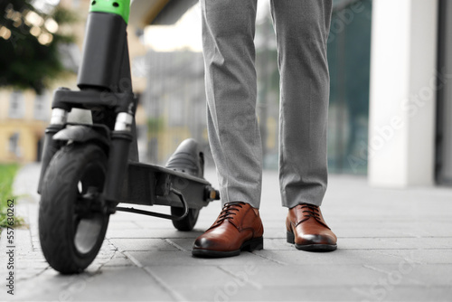 Businessman with modern kick scooter on city street, closeup