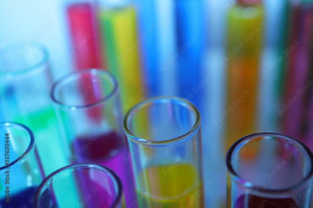 Many test tubes with colorful liquids on blurred background, closeup Many test tubes with colorful liquids on blurred background, closeup