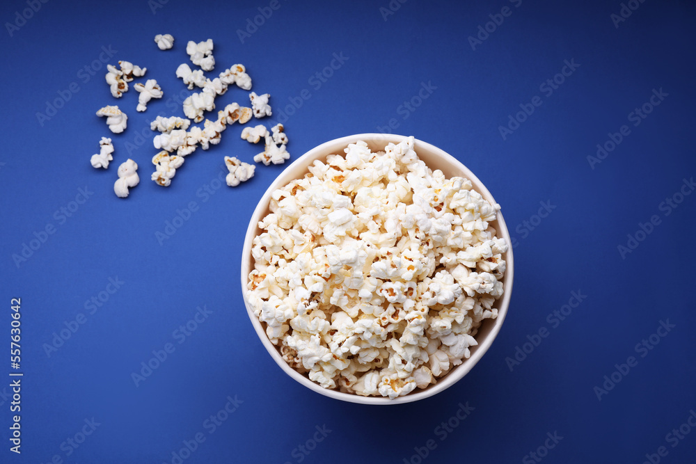 Bucket of tasty popcorn on blue background, flat lay Bucket of tasty popcorn on blue background, flat lay