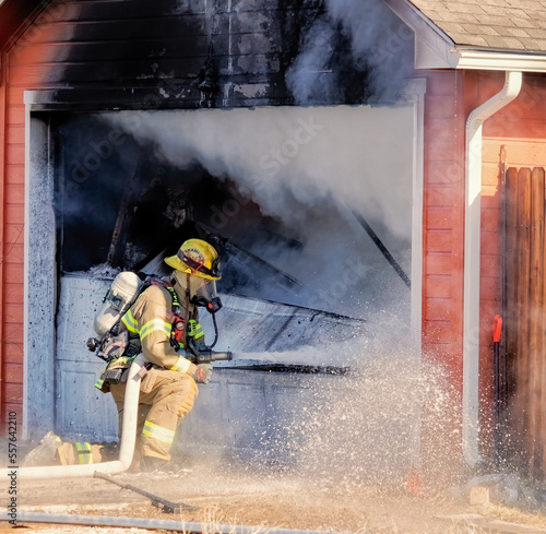 Firefighter uses a hose to battle a house fire