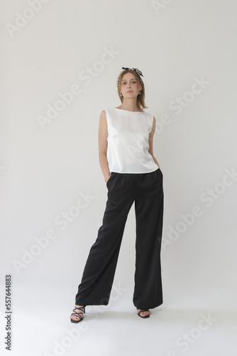 Serie of studio photos of young female model in black and white silk outfit, sleeveless blouse and wide legs trousers