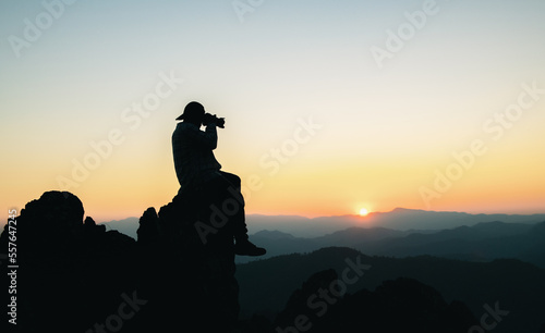 Backpacking hikers hold binoculars  relax on top of the mountain and enjoy views of the valley during sunset.
