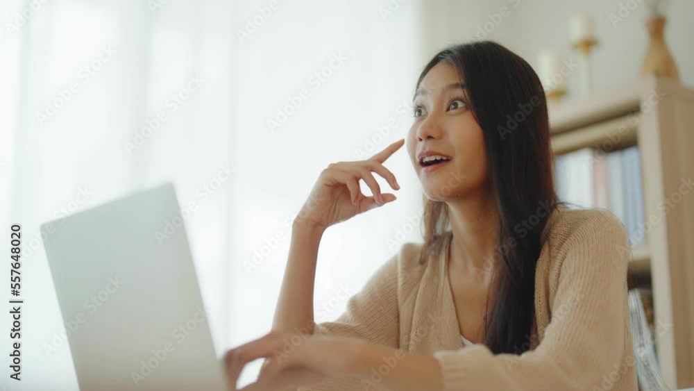 Young asian woman working on computer laptop on desk in living room at home Young asian woman working on computer laptop on desk in living room at home