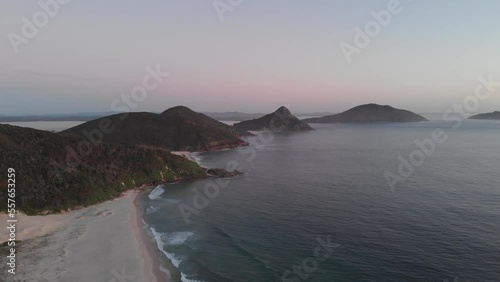 Sunrise drone video of the waves crashing against Fingal beach, facing toward Tomaree Mountain