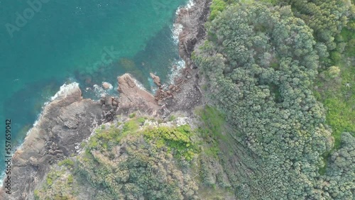 Drone video flying over the coastline of Shark Island, Fingal Bay with beautiful blue water and waves crashing on rocks