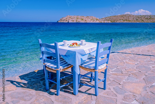 Crete Greece Plaka Lassithi with its traditional blue table and chairs and the beach in Crete Greece. Paralia Plakas, Plaka village Crete