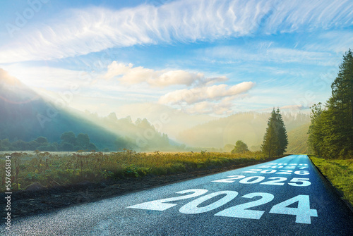 Obraz na płótnie road on which is written 2024 at sunrise in the mountains ilis.beginning 2024. morning fog near the forest and mountains and road. 2025. 2026. 2027. 2028. w salonie