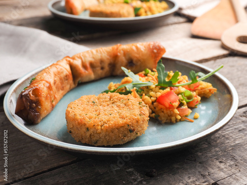 Tasty falafel with spicy bulgur and a vegetarian dough roll on a wooden table