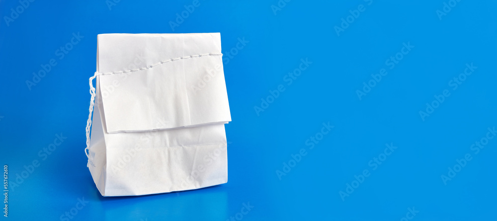 Paper bag sewn with thread on a blue background. Packaging of food products.