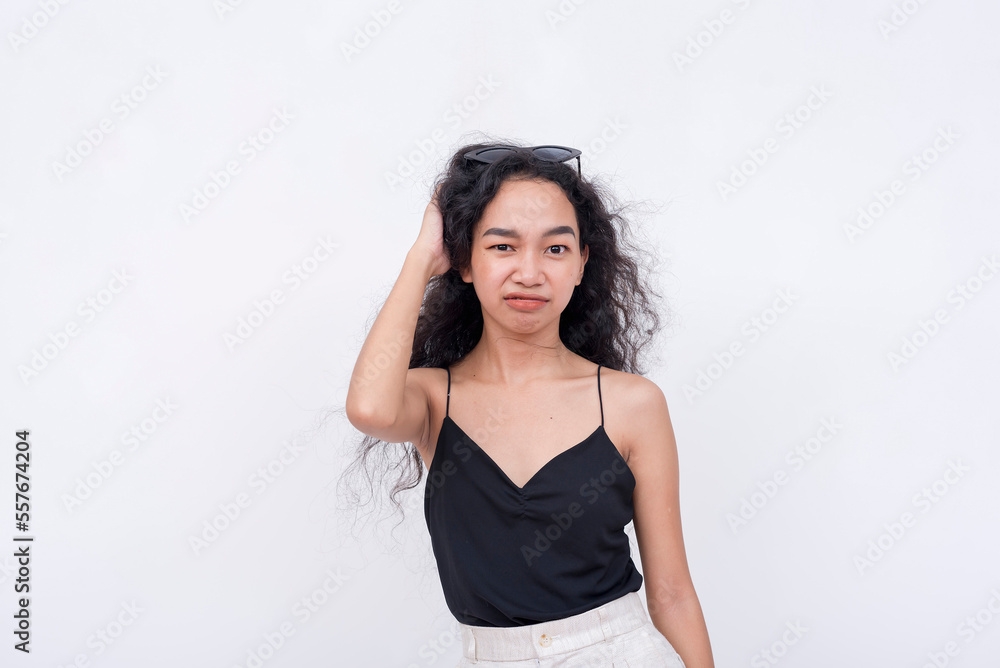 A frustrated young woman scratching her head while staring at the camera. Feeling irritated. Isolated on a white background. A frustrated young woman scratching her head while staring at the camera. Feeling irritated. Isolated on a white background.