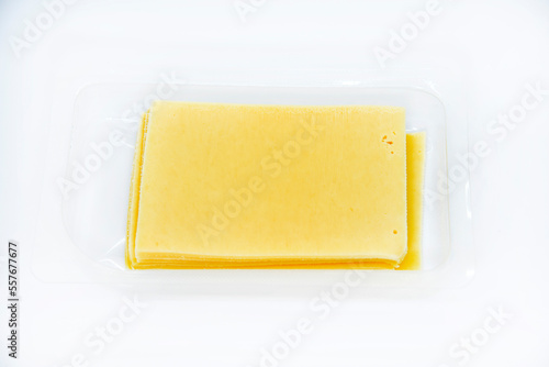Thinly sliced slices of cheese on a plastic backing. Delicious chopped yellow cheese. Cheese in a package from the store.