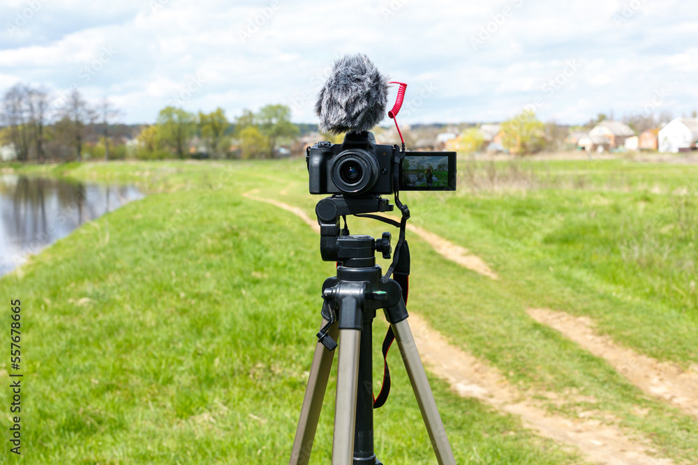 Digital camera with microphone on a tripod close-up. Mirrorless digital camera and microphone recording while broadcasting in nature Digital camera with microphone on a tripod close-up. Mirrorless digital camera and microphone recording while broadcasting in nature