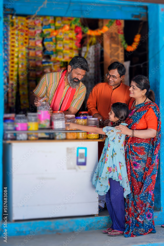 Indian little girl child purchasing some item with his mother at grocery store