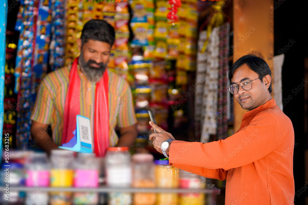 Indian rural customer using smartphone for digital payment at groceries shop Indian rural customer using smartphone for digital payment at groceries shop