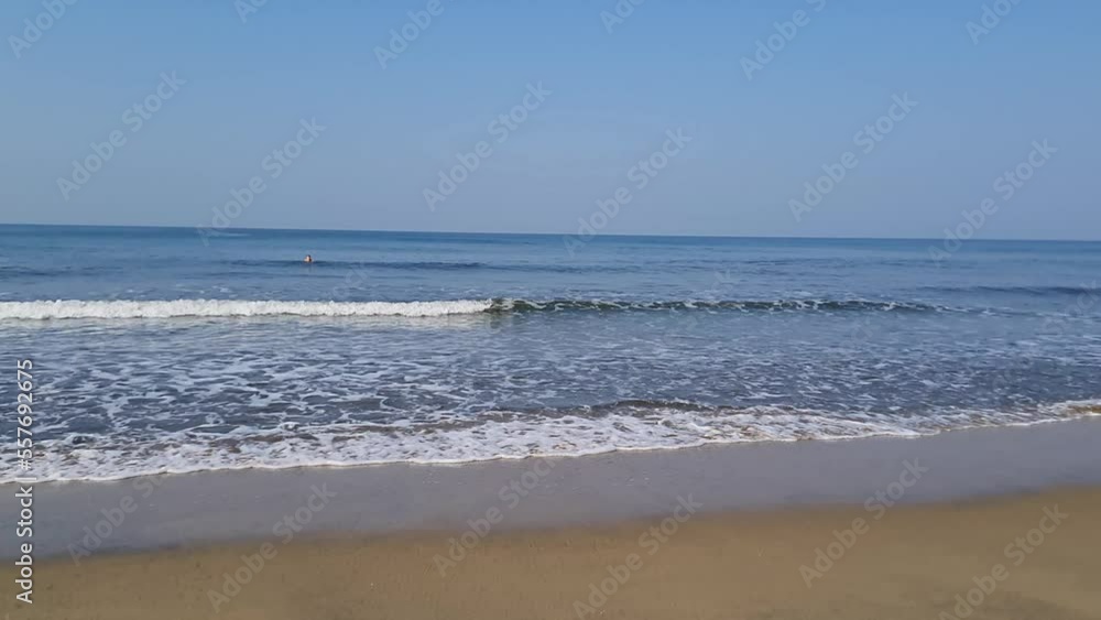 Wide view ocean coast beach with blue sky above and small waves Wide view ocean coast beach with blue sky above and small waves
