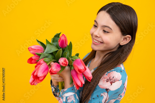 Cute teenage girl in beret hat hold spring tulip flowers on yellow background. Child with spring tulips bouquet, floral present.