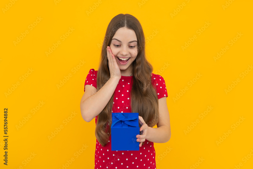 Teenager child holding gift box on yellow isolated background. Gift for kids birthday. Christmas or New Year present box. Valentines day. Teenager child holding gift box on yellow isolated background. Gift for kids birthday. Christmas or New Year present box. Valentines day.