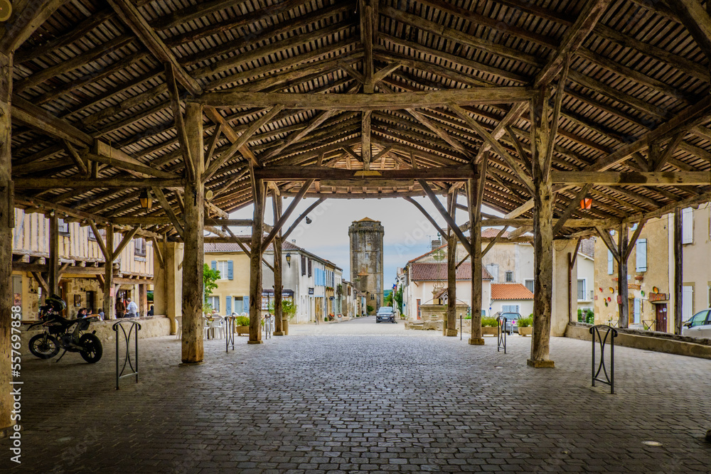 View on the main street and the medieval dungeon from the wooden covered market hall of Bassoues (South of France, Gers)