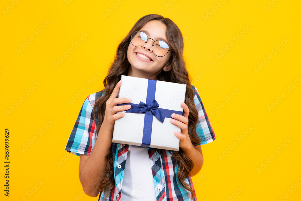 Portrait of a teenager child girl holding present box isolated over yellow studio background. Present, greeting and gifting concept. Birthday holiday concept. Portrait of a teenager child girl holding present box isolated over yellow studio background. Present, greeting and gifting concept. Birthday holiday concept.