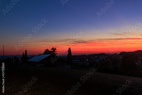 colorful sunset in Rems-Murrkreis district in Germany with view of roof with solar panels and silhouette of tree