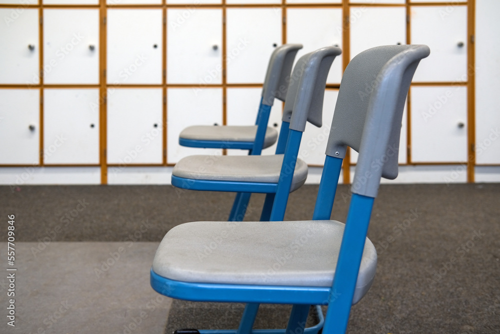 Seitenansicht auf drei leere Stühle in einem Klassenzimmer oder Seminar- oder Konferenzraum oder einer ähnlichen Einrichtung mit Schrankfächern im Hintergrund