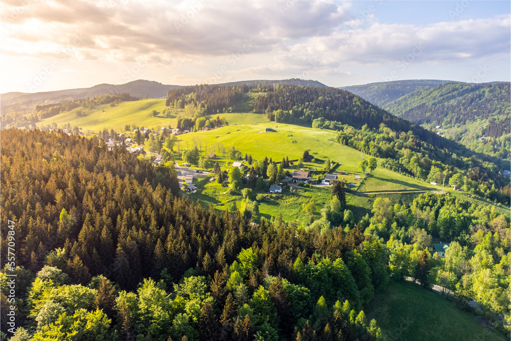 Albrechtice v Jizerskych horach town in the middle of green hills of Jizera mountains on sunny summer day. Czech Republic. Aerial view from drone.