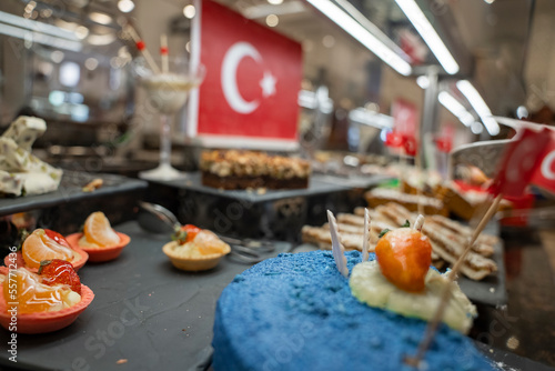 Close-up of half-eaten blue cake garnished with fruits and various desserts served with Turkish flags at restaurant in buffet © Aerial Film Studio