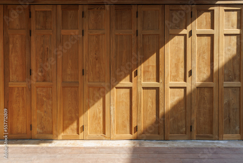 vintage old wooden thai bi folding facade. light and shadow on foldable timber door in thai style.