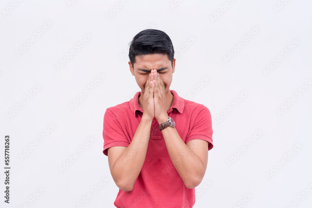 A man tries to contain his laughter, covering his face with his hands, but visibly struggling. Isolated on a white background. A man tries to contain his laughter, covering his face with his hands, but visibly struggling. Isolated on a white background.