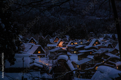 Lights from traditional houses glow in snowy mountain village at night photo