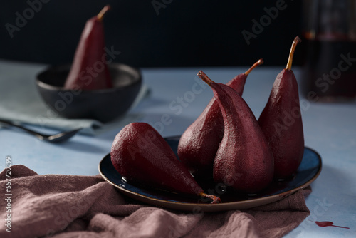 Poached pears in red wine on a blue plate and wood background