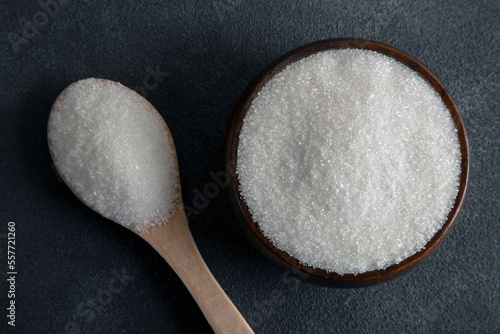 Granulated sugar in bowl on dark background