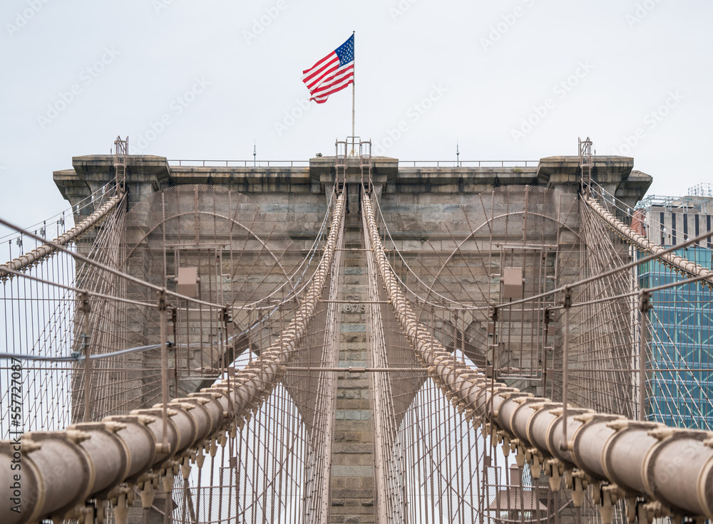 Obraz premium American flag in the wind on top of the Brooklyn bridge in New York City, USA