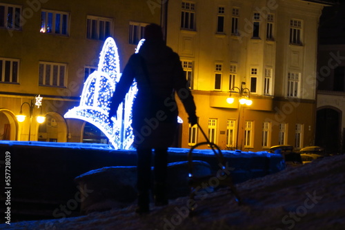 old city center of kremnica in dark night with illumination and fountain with light together with contour of beautiful lady in cold winter in slovakia