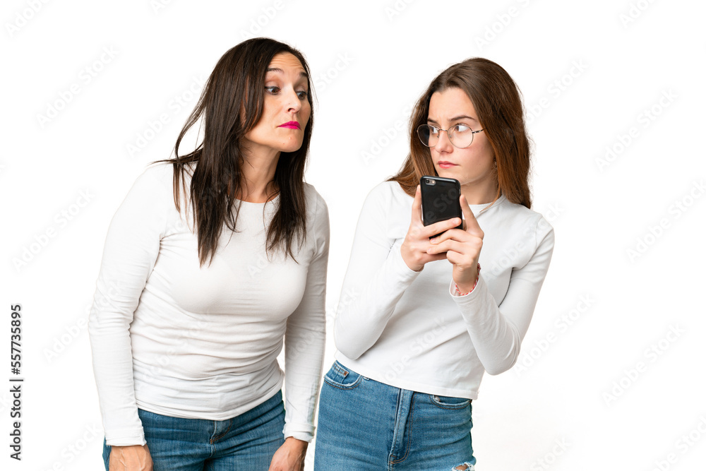 mother and daughter over isolated chroma key background reading a message with the mobile mother and daughter over isolated chroma key background reading a message with the mobile