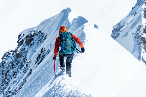 Mountain climber on a steep narrow snow ridge, extreme alpinist mountaineer, Monch, Bernese Alps, Swiss