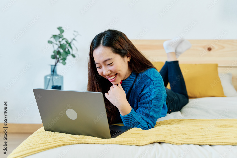 Positive young female in casual clothes sitting on bed and browsing laptop while working on remote project at home Positive young female in casual clothes sitting on bed and browsing laptop while working on remote project at home