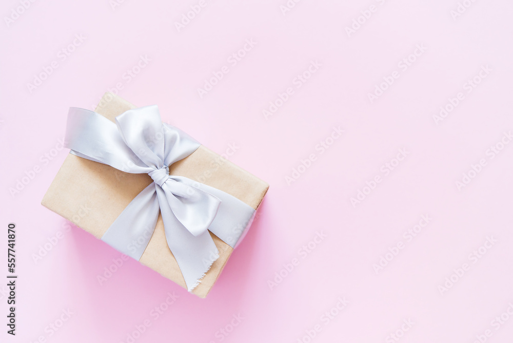 Rectangular gift box with silver ribbon on plain light pink background