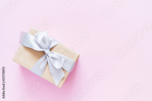 Rectangular gift box with silver ribbon on plain light pink background