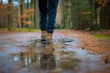 Selective focus shot of hiking boots walking through a puddle of water in the forest