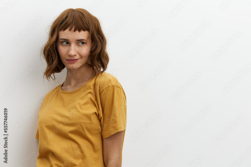 a beautiful, sweet, relaxed woman stands on a light background in a yellow T-shirt and looks away with a pleasant smile. Horizontal photo with an empty space for inserting an advertising layout a beautiful, sweet, relaxed woman stands on a light background in a yellow T-shirt and looks away with a pleasant smile. Horizontal photo with an empty space for inserting an advertising layout