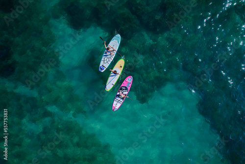 Aerial drone view of a couple of paddle surfers over crystalline waters. High-quality 4k footage © Dronemetrics