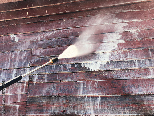 Washing with a high-pressure apparatus of a wooden red wall of a residential building from boards photo