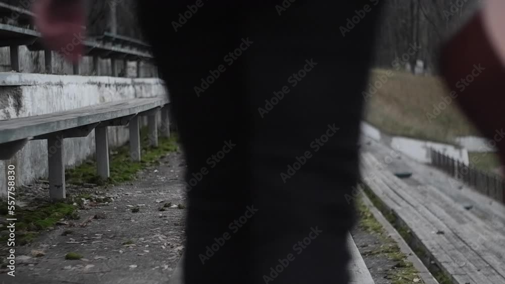 Close up woman in black walks with a guitar along a wooden bench in an old stadium outside, music concept. Vintage cinematic lifestyle Close up woman in black walks with a guitar along a wooden bench in an old stadium outside, music concept. Vintage cinematic lifestyle
