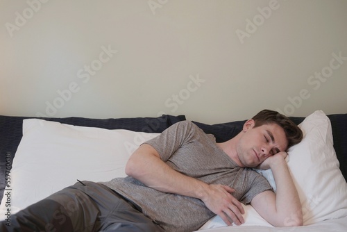 young man sleeping in grey clothes on the bed