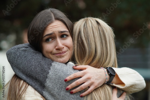 Hypocritical girl hugs a friend but gets bored of being close to her. Fake Friendship concept photo